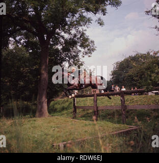 1960 s, Burghley Horse Trials, cross country Event..... einen männlichen Konkurrenten auf Horse Jumping ein Hindernis auf dem Wald. Diese jährliche 3-tägige Veranstaltung ist eines der besten Turniere der Welt und die längste laufende internationale Veranstaltung. Stockfoto