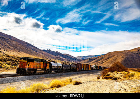 Ein BNSF Güterzug Richtung Westen in Richtung Tehachapi Kalifornien mit einem Drücker Lokomotive auf der Rückseite des Zug Stockfoto