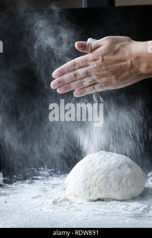 Der Teig mit Mehl durch femae Hände Stockfoto