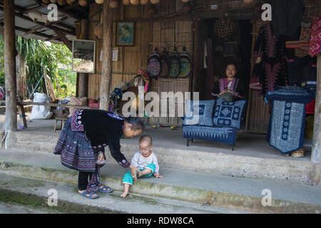 Hmong Thailand Frau und Baby Mutter Großmutter vor dem Haus Shop Holz verkaufen Kleidung Stoff Stufen Kunst Designs Stoff verkaufen Stockfoto