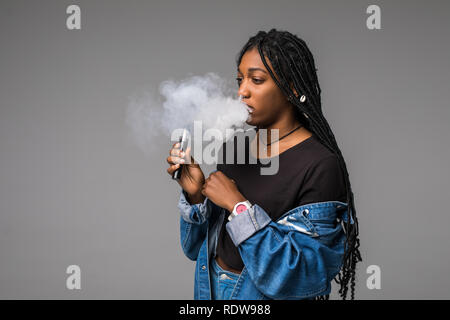 Seitenansicht Portrait von Guy Holding vape Gerät und Ausatmen Wolke von Rauch auf blauem Hintergrund isoliert. Stockfoto