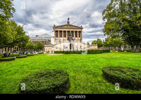 Touristen besuchen die National Gallery oder Alte Nationalgalerie an einem bewölkten Tag auf der Museumsinsel in Berlin, Deutschland. Stockfoto