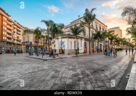 Geschäfte an der Hauptstraße Corso Umberto, wie die Einheimischen am frühen Abend spazieren, oder Passeggiata, in Brindisi Italien, in der Region Apulien genießen. Stockfoto