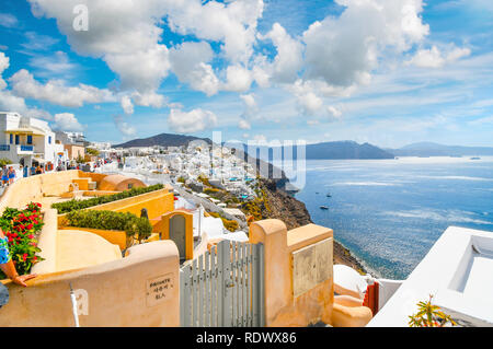 Einen malerischen Blick auf die Caldera von Santorin und die Ägäis von einem Resort Terrasse als Touristen zu Fuß die Hauptstraße in den Hang Dorf Oia, Music Stockfoto