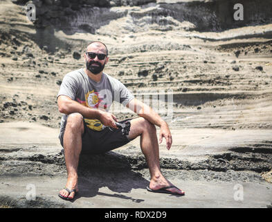 Junger Mann mit Bart Standortwahl auf die sandige Wüste Bank Bali Indonesien Stockfoto