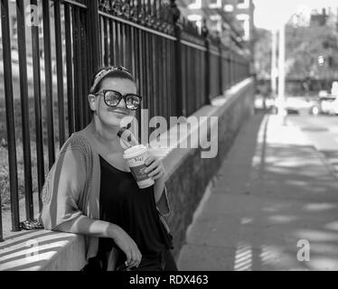 Junge Frau auf der Straße trinken Kaffee und Standortwahl auf der Seite zu Fuß durch die rote Tür Stockfoto