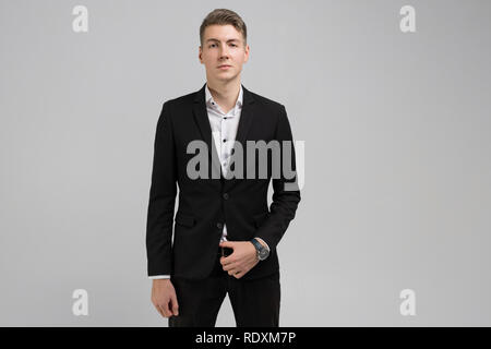 Portrait des jungen Mannes im schwarzen Anzug auf weißem Hintergrund Stockfoto