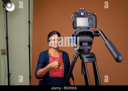 Reifen schöne indische Frau vlogging im Studio mit Kamera Stockfoto