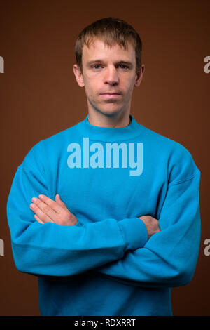 Mann mit blauen Pullover gegen braunen Hintergrund Stockfoto