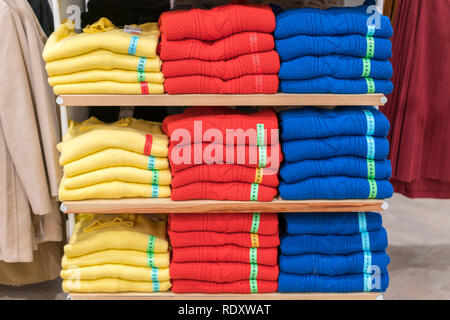 Ordentliche Stapel gefalteter Kleidung auf die Regale. Farbe Faltung shirt In einer durchorganisierten Clothing Store Stockfoto