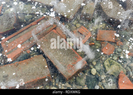 Winter Hintergrund. Ziegel und Steine unter dem Eis Stockfoto