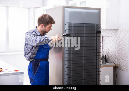 Soldaten in insgesamt Arbeiten am Kühlschrank mit Schraubenschlüssel in der Küche Stockfoto