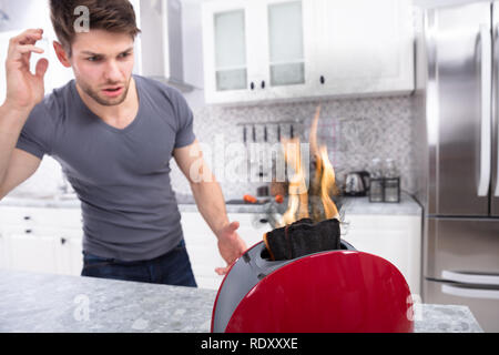 Portrait von Furchtsamen Mann auf Scheibe brennen Aus Toaster Stockfoto