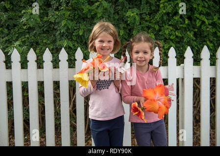 Zwei junge Model Released Schwestern pose mit Blumen, die Sie beim Urlaub in der bezaubernden Stadt von Russell abgeholt. Stockfoto