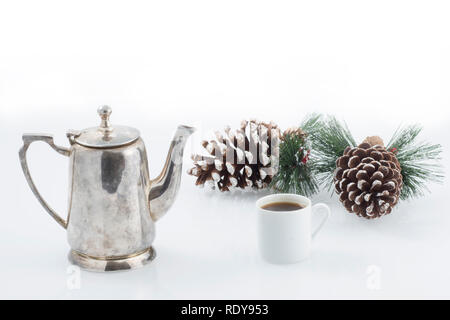 Vintage Zinn Kaffeekanne, eine weiße Tasse, und zwei große Tannenzapfen auf einem weißen Hintergrund. Stockfoto