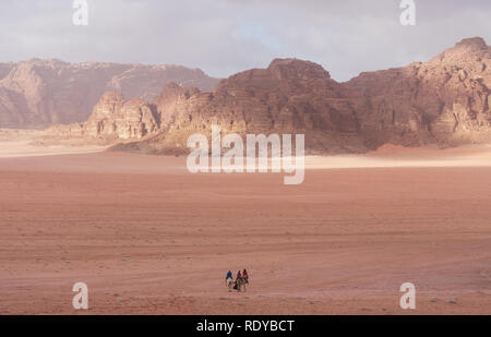 Wadi Rum wüste Landschaft in Jordanien mit Touristen reiten Kamele am Morgen Stockfoto