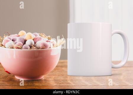Pretty Pink Schüssel mit mini Schokolade Eier in, neben einem weissen Kaffeebecher. Perfekt für Unternehmen Tassen verkaufen, nur overlay Ihre Angebots- oder Design auf Stockfoto
