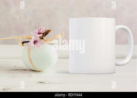 Leere weiße Tasse weiter zu einem kleinen Zweig von Blume, auf einem Tisch. Perfekt für Unternehmen Tassen verkaufen, nur Overlay ihr Angebot oder Design auf, das im Stockfoto