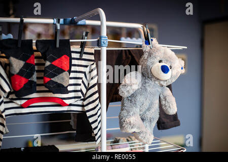 Grau Teddybär Plüsch Spielzeug hängend trocknen mit Wäsche Kleidung nach gewaschen wird. Von der Seite. Stockfoto