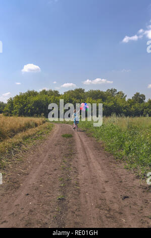 Konzept Bild der Reise von Glück und childness mit Frau im Kleid mit bunten Luftballons auf dem Fahrrad Stockfoto