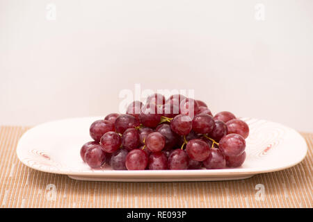 Rote Trauben auf einem Teller und Tisch frisch und nass und süß lecker Stockfoto