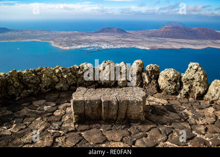 Eine Steinbank mit Blick auf die Insel La Graciosa von Mirador del Rio auf Lanzarote, Kanarische Inseln Stockfoto