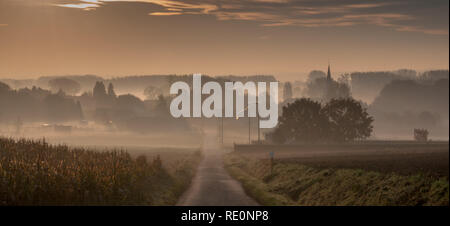 Ein kleines Dorf in Ost- Flandern wird in einem frühen Morgennebel bedeckt. Sonnenaufgang auf einem späten Herbst morgen. Stockfoto
