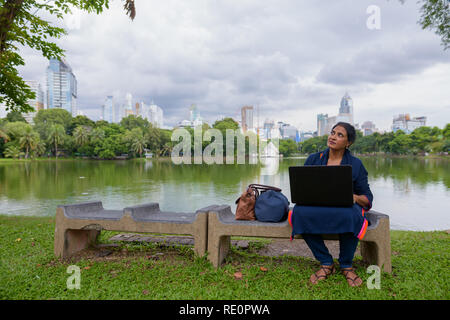 Portrait von Reifen der indischen Frau im Park mit Laptop Stockfoto