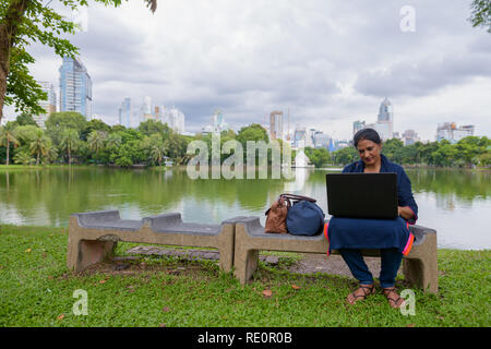 Portrait von Reifen der indischen Frau im Park mit Laptop Stockfoto