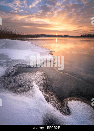 Malerische Winterlandschaft mit gefrorenen See und Sonnenuntergang am Abend Zeit in Finnland Stockfoto