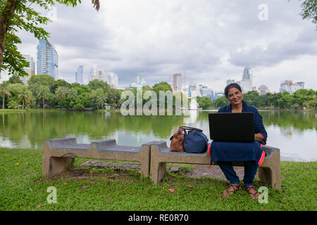 Portrait von Reifen der indischen Frau im Park mit Laptop Stockfoto