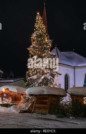 SEEFELD, Österreich - Januar 07, 2019: Nachtansicht von St. Oswald Pfarrkirche in Seefeld in Tirol mit einem riesigen schneebedeckten Christus Stockfoto
