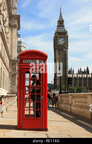 Ein Mann mit dem Telefon in einem typischen britischen Telefonzelle auf dem Bürgersteig mit dem berühmten Elizabeth Tower (Big Ben) im Hintergrund - London, Großbritannien Stockfoto