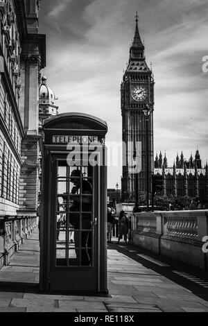 Ein Mann mit dem Telefon in einem typischen britischen Telefonzelle auf dem Bürgersteig mit dem berühmten Elizabeth Tower (Big Ben) im Hintergrund - London, Großbritannien Stockfoto