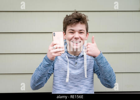 Männliche teenager Daumen nach oben, während sie seine neue Apple iPhone X Stockfoto