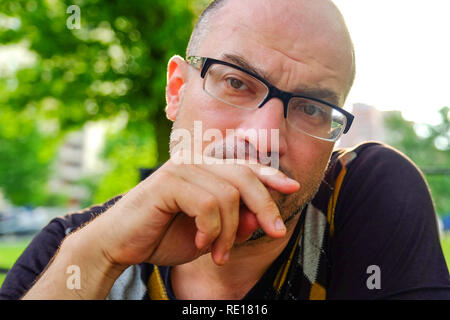 Der Mann mit der Brille leidet unter Depressionen. Probleme im persönlichen Leben und bei der Arbeit. Stress und Depressionen. Migräne ist eine Folge von Stress. Stockfoto