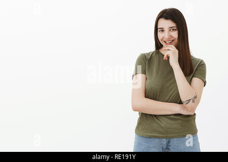 Freche kreative und kluge Frau haben interessante Idee grinsend aus Freude und Interesse die Hand am Kinn amüsiert und an der Kamera begeistert, Weiß Stockfoto