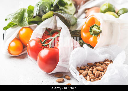 Gemüse in eco Baumwolltaschen, Pfeffer, Tomaten, Kopfsalat, Gurken, Kalk, Zwiebel auf weißem Hintergrund. Null Abfall Lebensmittel einkaufen. Stockfoto