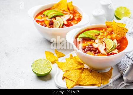 Mexikanische Suppe mit Bohnen, Hühnchen, Mais und Nachos in weißen Schalen. Chili con Carne - traditionelle mexikanische Küche. Stockfoto