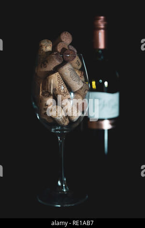 Haufen sortierte Weinkorken Wein Glas auf schwarzem Hintergrund Stockfoto