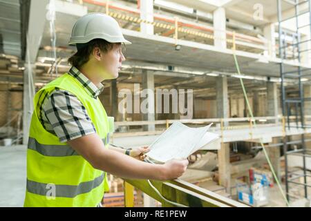 Junge männliche Architekt auf einer Baustelle. Gebäude, Entwicklung, Teamwork und Personen Konzept. Stockfoto