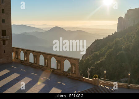 Mit Blick auf das Kloster von Montserrat. Steinstatuen und Bögen auf der Außenseite mit Bergen im Hintergrund in den frühen Morgenstunden. Barcelona, Spanien. Stockfoto