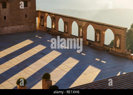 Mit Blick auf das Kloster von Montserrat. Steinstatuen und Bögen auf der Außenseite mit Bergen im Hintergrund in den frühen Morgenstunden. Barcelona, Spanien. Stockfoto