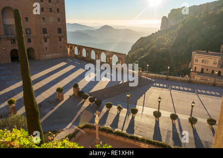 Mit Blick auf das Kloster von Montserrat. Steinstatuen und Bögen auf der Außenseite mit Bergen im Hintergrund in den frühen Morgenstunden. Barcelona, Spanien. Stockfoto