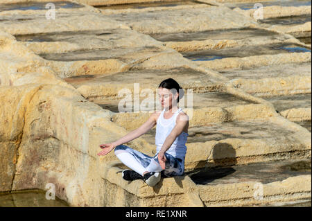Frau, Meditation, sitzen unter der Kalkstein Salinen in Malta Stockfoto