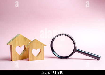 Zwei Holz- Haus mit einem Herz und einer Lupe. Das Konzept der Suche nach erschwinglichen Wohnraum für junge Familien und Ehepaare. Hypothek. Mieten Stockfoto