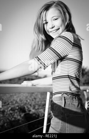 Happy tween lächelt, während sich stützen auf dem Balkon draußen in Schwarz und Weiß Stockfoto