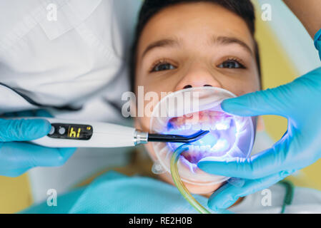 Einbau der Dichtung Prozess, Kinderzahnheilkunde, Kinder Stomatologie. Weiblichen Zahnarzt arbeitet mit kleinen Jungen in der zahnmedizinischen Klinik Stockfoto