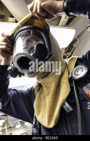 Mediterranen MEER (Nov. 9, 2016) Pettyu Officer 3. Klasse Lukas Schmalix aus Brooklyn, N.Y., zieht ein Flash Haube während einer Klasse bravo Brandschutzübung an Bord der USS Ross (DDG71) Nov. 9, 2016. Ross, einer der Arleigh-Burke-Klasse geführte-missile Destroyer, Vorwärts - Rota, Spanien bereitgestellt werden, ist die Durchführung von naval Operations in den USA 6 Flotte Bereich der Maßnahmen zur Unterstützung der US-amerikanischen nationalen Sicherheitsinteressen in Europa und Afrika. Stockfoto