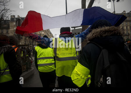 Paris, Frankreich. . Jan, 2019 19. Ein Demonstrant hält eine französische Flagge mit dem Slogan auf seine Weste 'Macron Rücktritt" bei einer Demonstration gegen den französischen Präsidenten Längestrich Politik. Gelbe weste Demonstranten versammelt und marschierten auf den Straßen von Paris ein weiteres Samstag auf, was Sie die Akte X gegen die Politik der französische Präsident Emmanuel's Längestrich nennen. Credit: Bruno Thevenin/SOPA Images/ZUMA Draht/Alamy leben Nachrichten Stockfoto